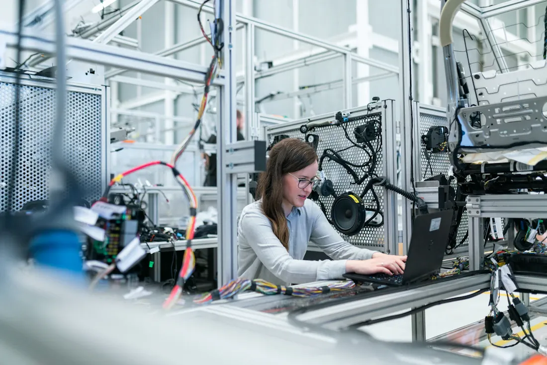 Ingénieure travaillant sur un ordinateur portable dans un atelier équipé.