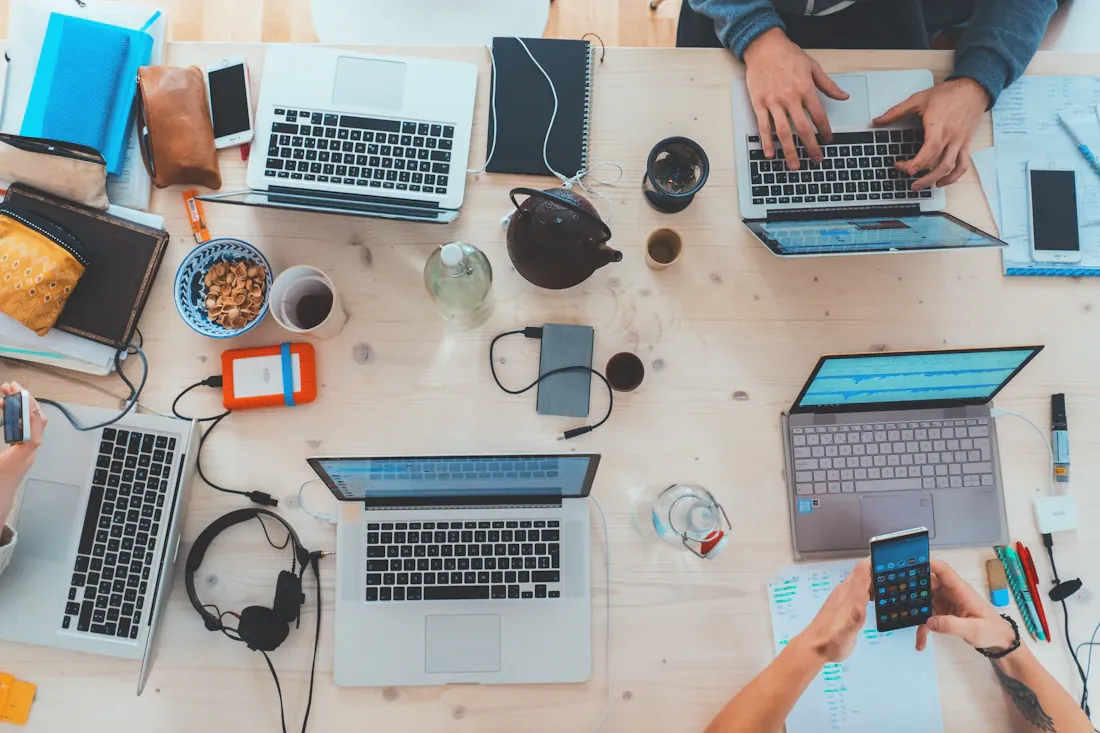 Vue du dessus d’une table partagée avec ordinateurs, tablette et accessoires de travail.